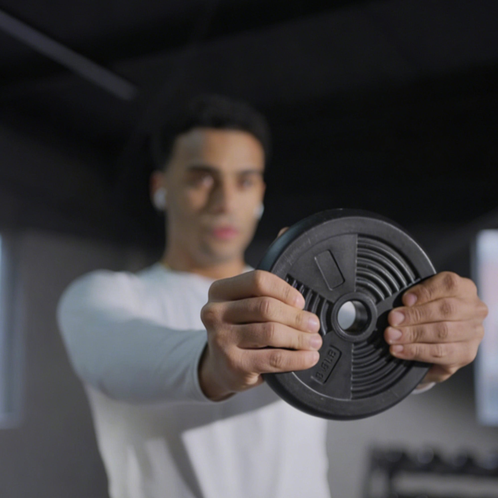 Person holding a weight plate in a gym setting