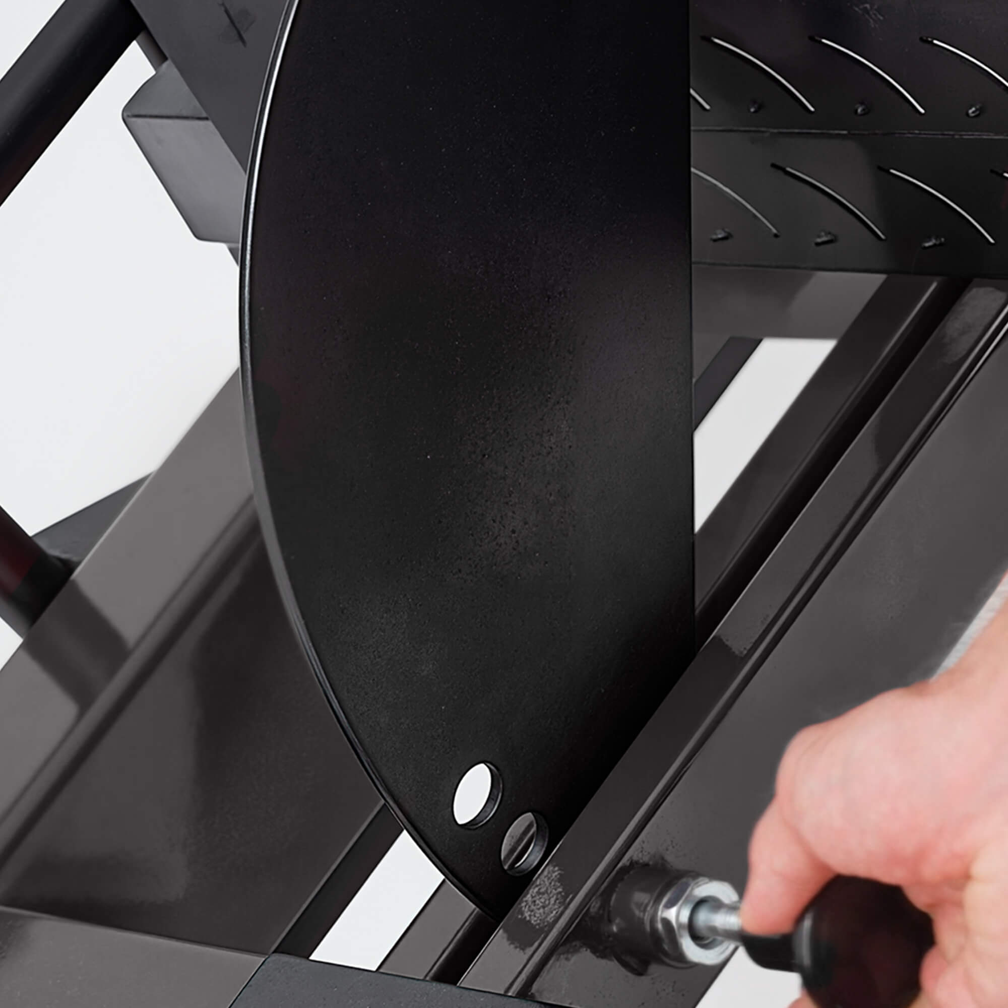 Person using a screwdriver to tighten a screw on a black metal object.#color_black
