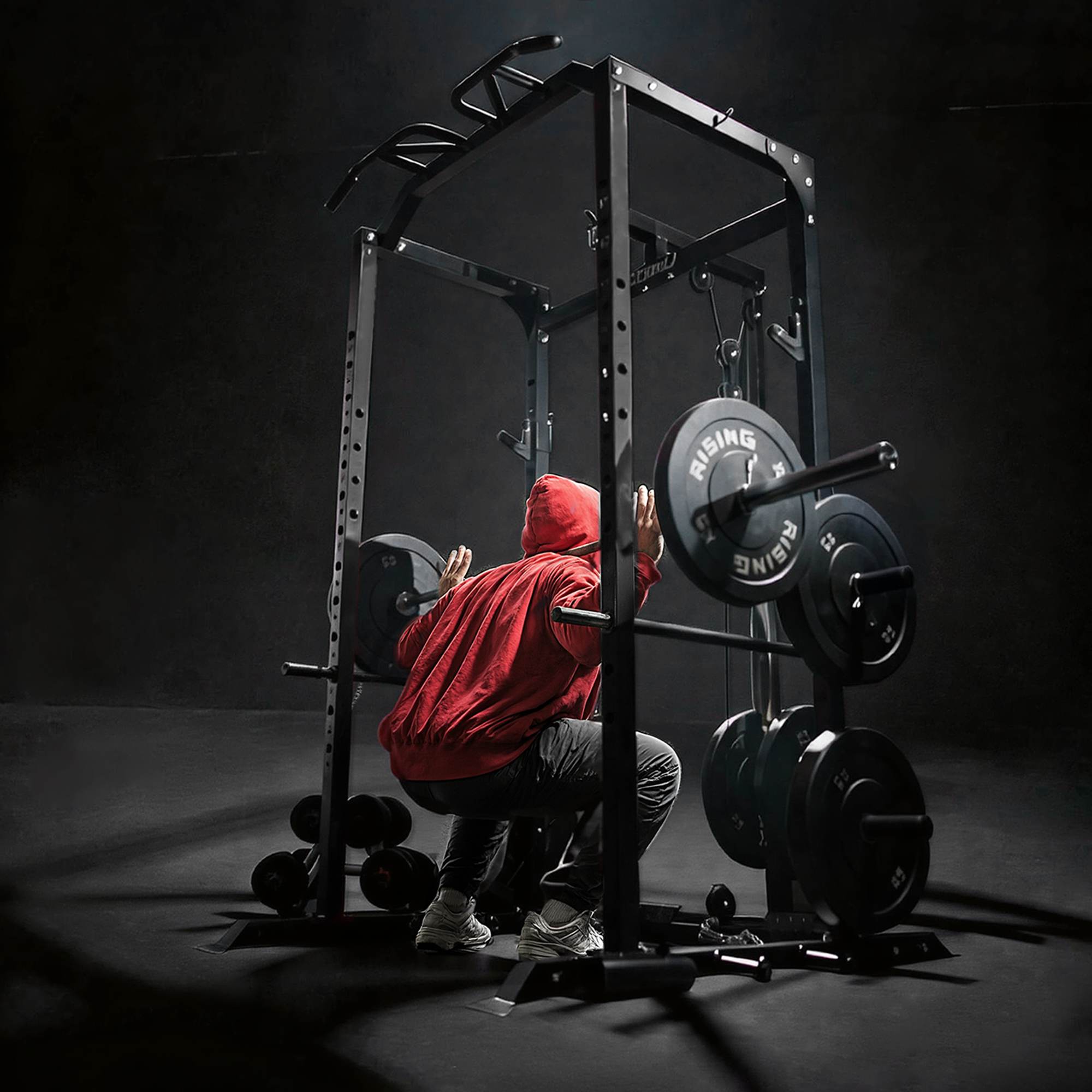 Person in a red hoodie using a weightlifting machine in a dark gym.
