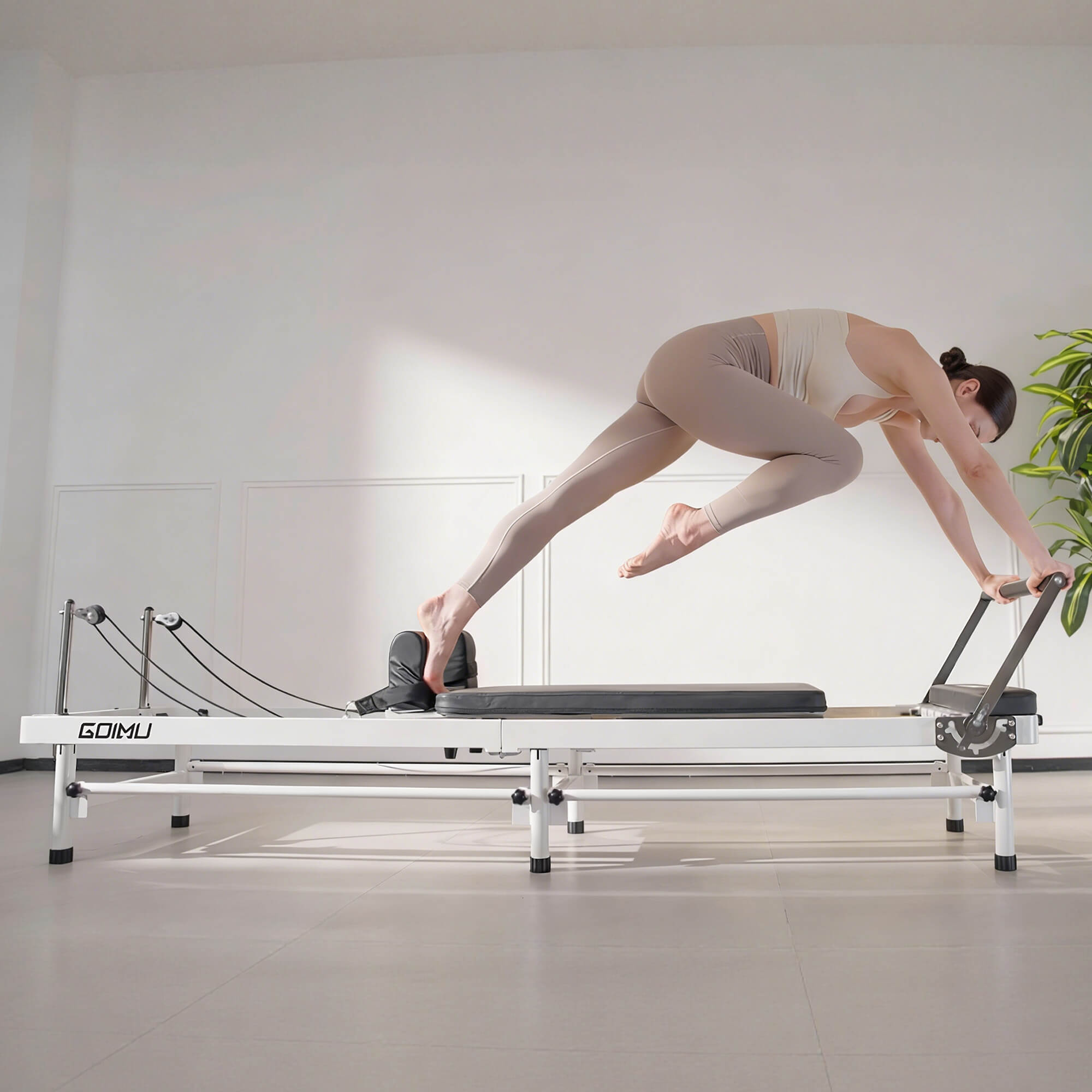 Woman exercising on a Pilates reformer machine in a studio setting.