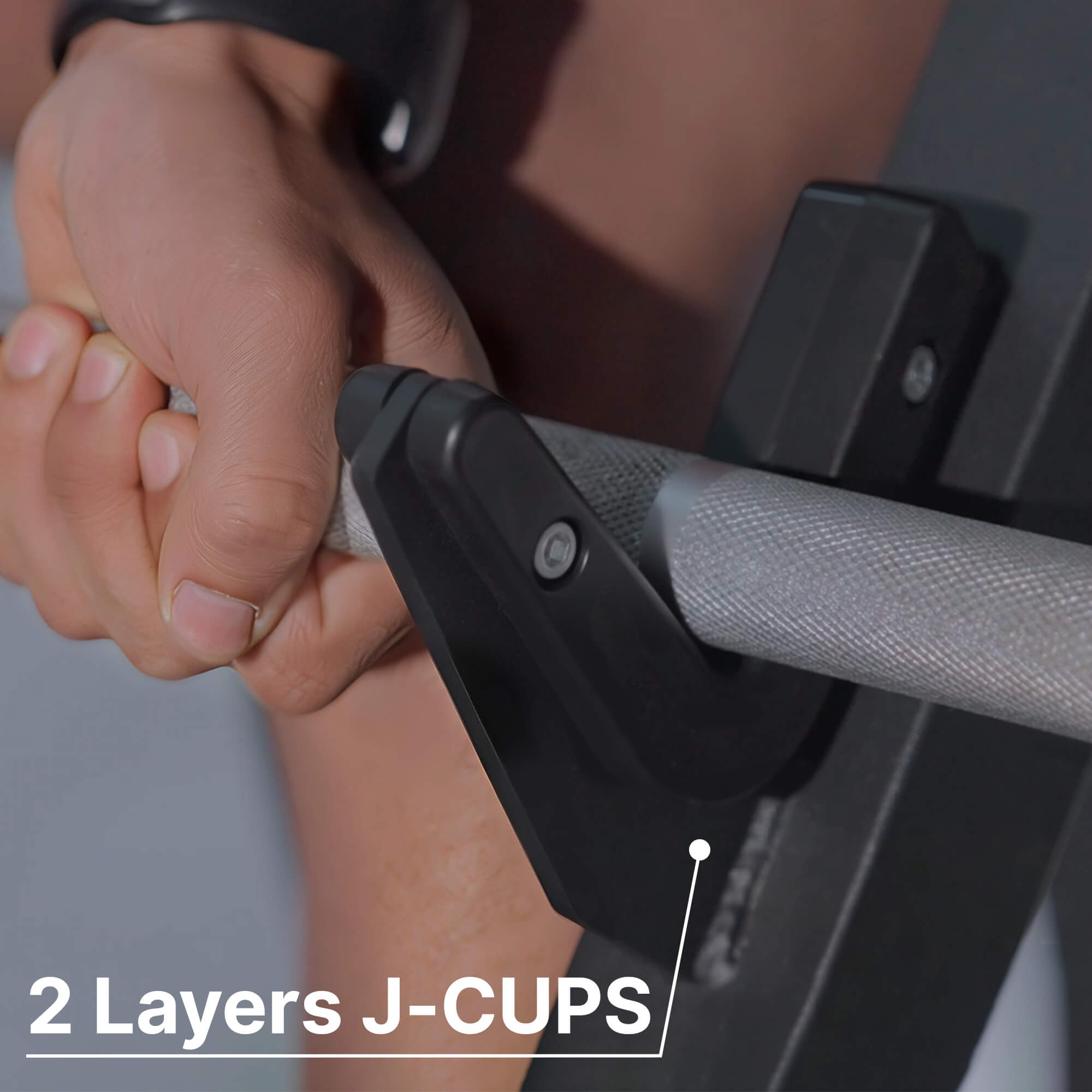 Close-up of hands gripping a barbell with '2 Layers J-CUPS' text.#color_black