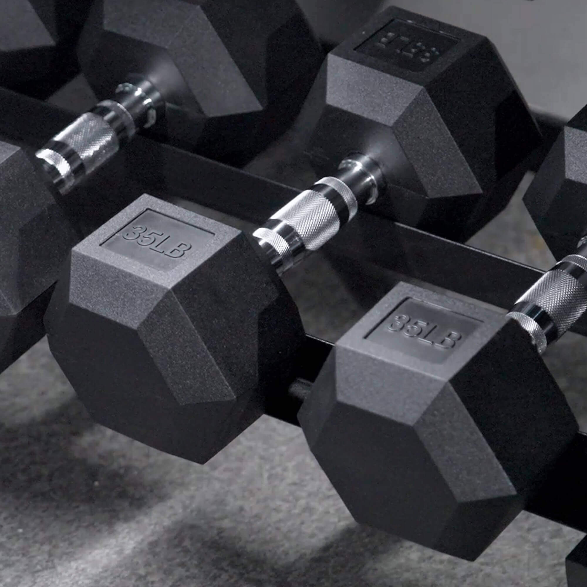 Pair of hexagonal dumbbells with weight markings on a textured surface.#pounds_360lbs-with-rack