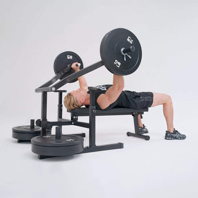 Person performing a bench press with a barbell on a weight bench against a white background.#color_black