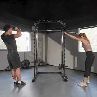 Two people setting up a power rack in a home gym.