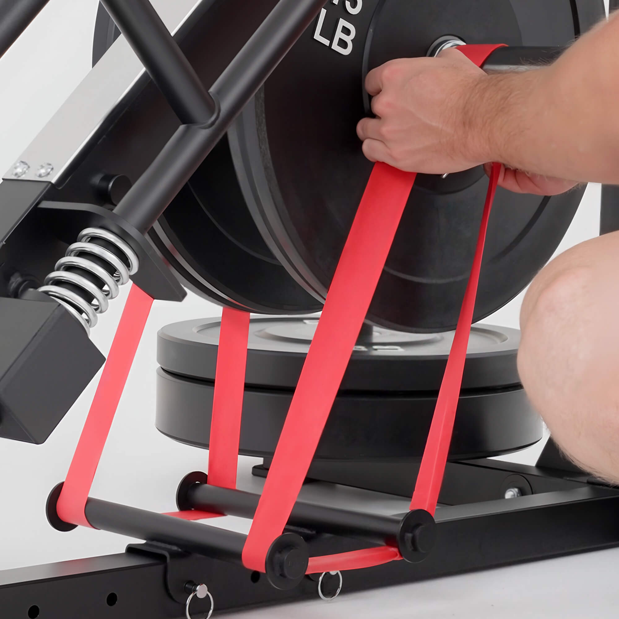 Person using a resistance band with a weight machine in a gym setting.#color_red