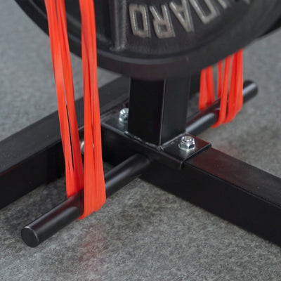 Close-up of a black exercise machine with red resistance bands on a gray floor.