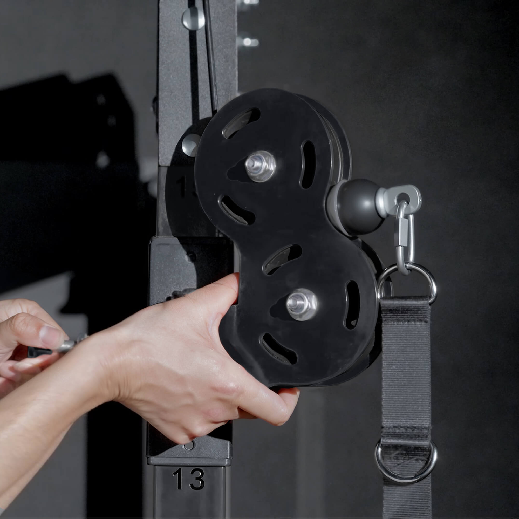 Person holding a black pulley system with a blurred gym background.
