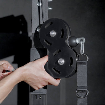 Person holding a black pulley system with a blurred gym background.