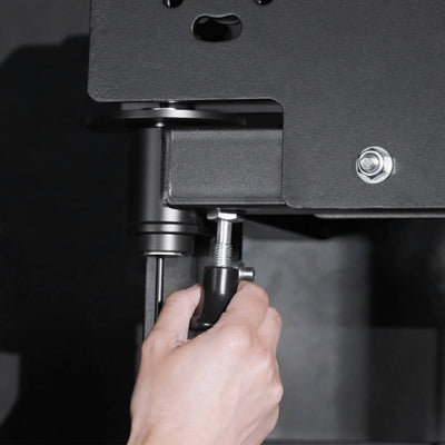 Hand adjusting a screw on a piece of equipment with a dark background.