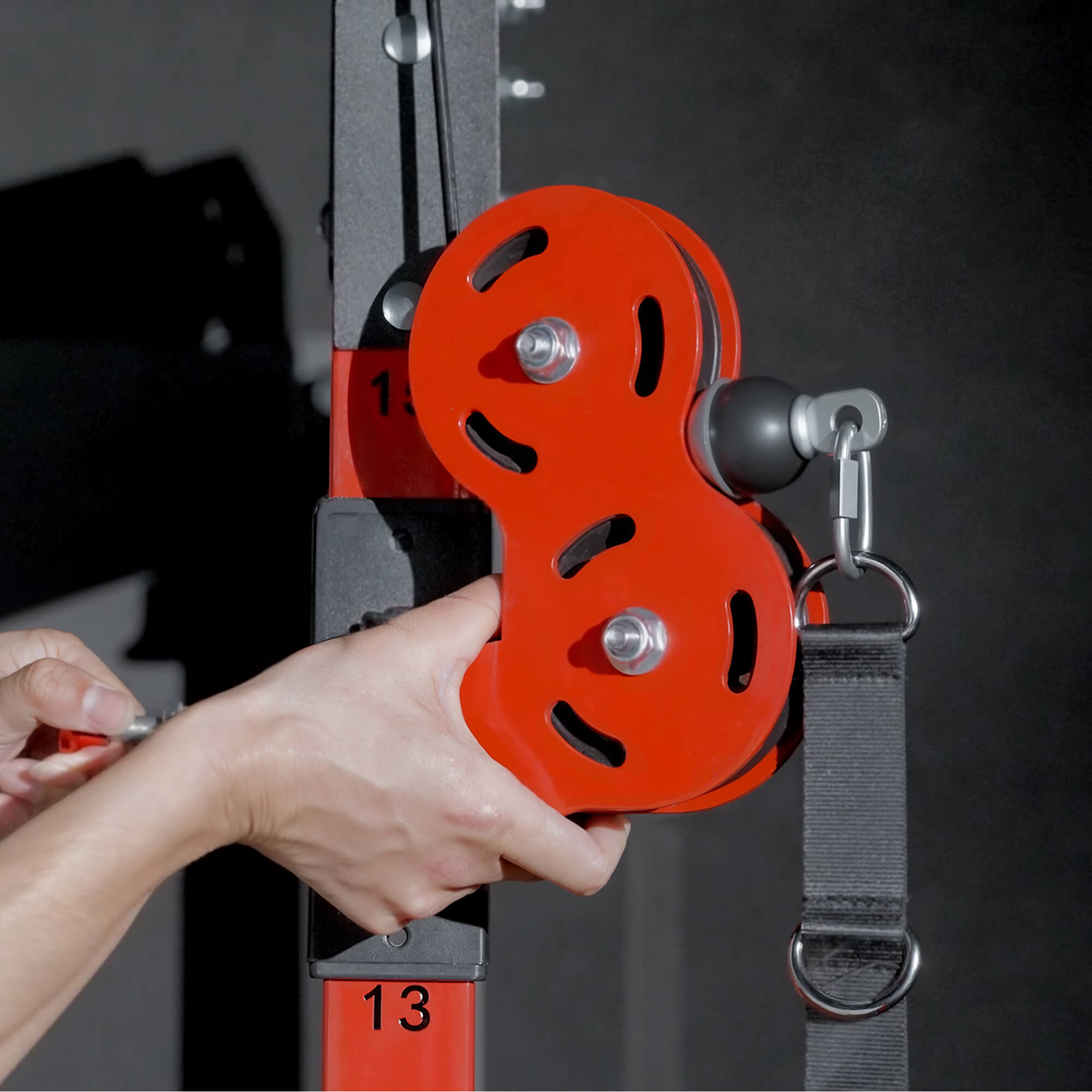 Person holding a red pulley system with a dark background.