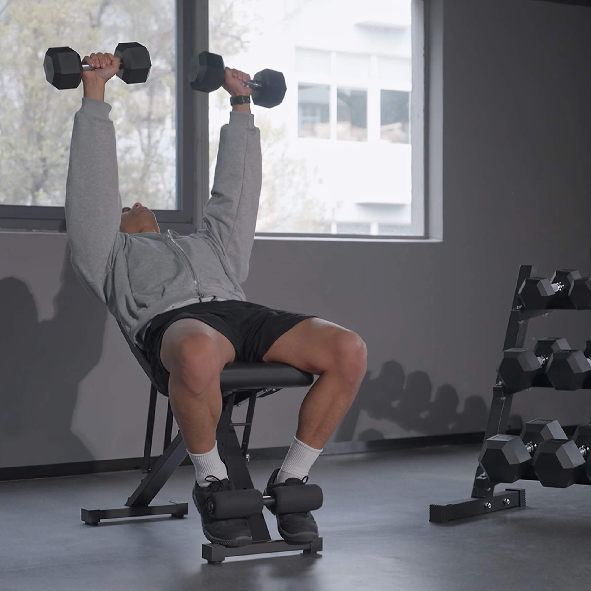 Person using a weight bench with dumbbells in a gym setting.#pounds_280lbs-with-rack