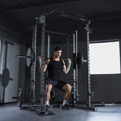 Man performing squats with a barbell in a gym setting.