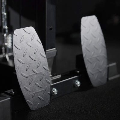 Close-up of two metallic foot pedals with textured surfaces on a dark background.